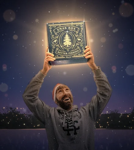 Victor hält die leuchtende Better XMAS Box am See in die Höhe