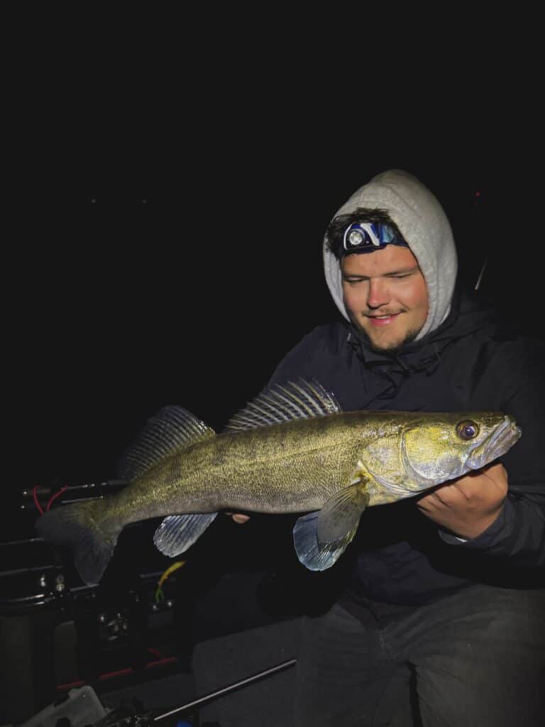 Angler zeigt nachts einen Zander